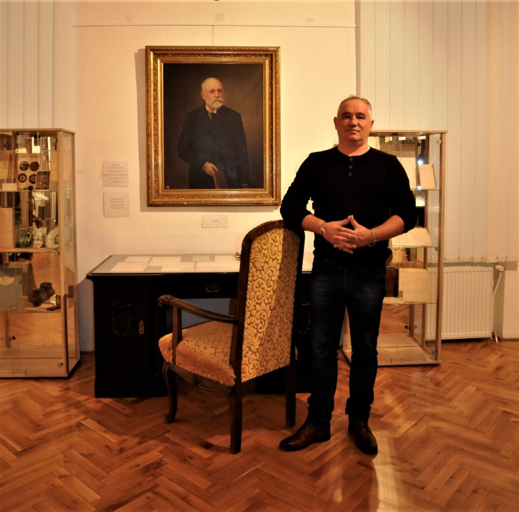 Pohľad na výstavu - prapravnuk Jánosa Fábryho Szabolcs Fábry, v pozadí portrét Jánosa Fábryho s písacím stolom.